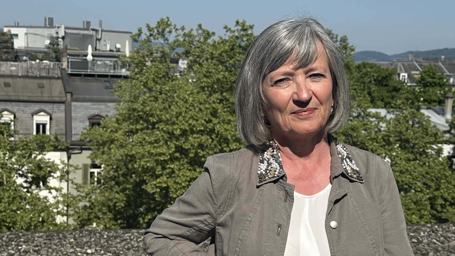 A woman on a balcony, in the background is Zurich.