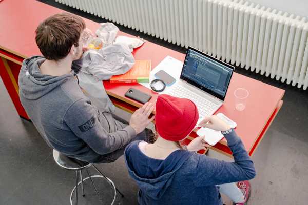 Eine Teilnehmerin und Dominic Weibel programmieren beim Kuchenessen