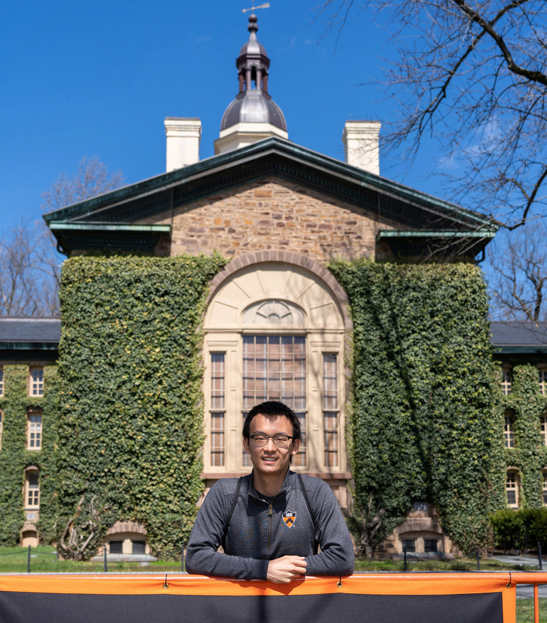 Vergrösserte Ansicht: Daniel Yang steht vor der Nassau Hall, einem mit Efeu bewachsenen neugotischen Gebäude