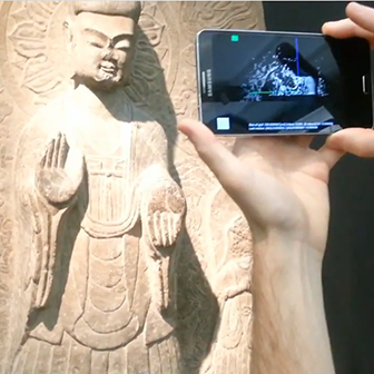 Person pointing a smartphone at a statue