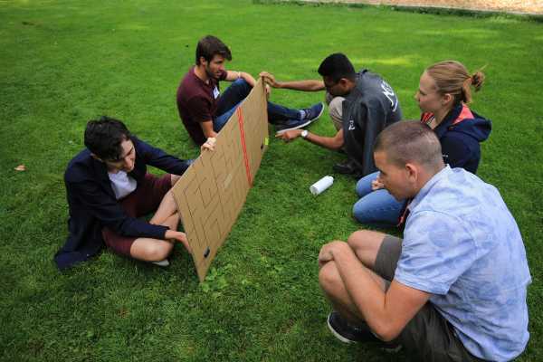 Participants sitting in the grass with a cardboard game.