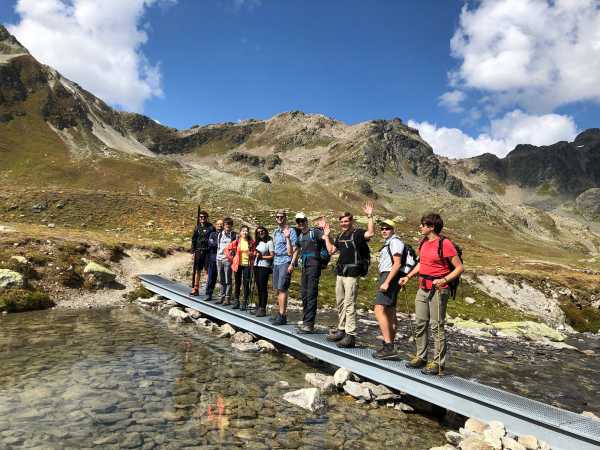Participants on a narrow footbridge in the mountains.