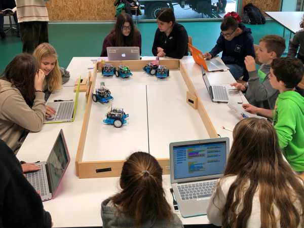 children around a table with computer and small self-driving robots