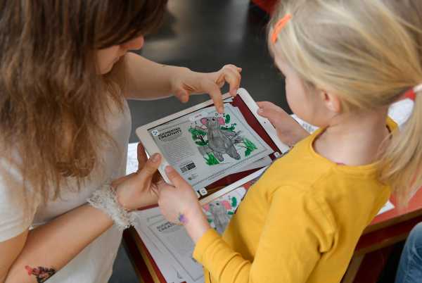 Eine Helferin erklärt einem Kind das iPad.